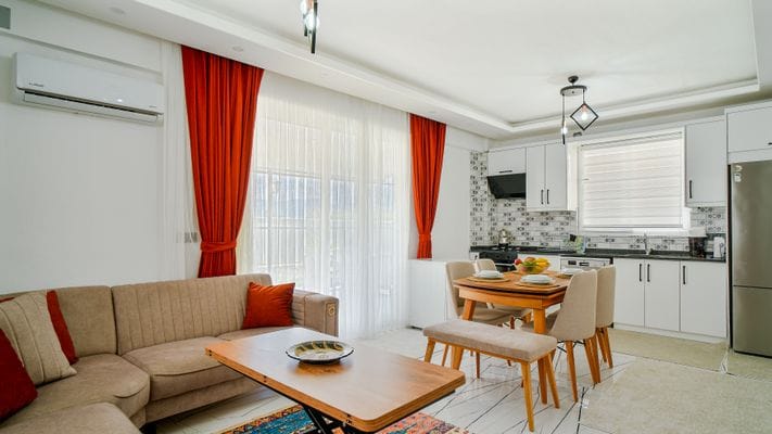 Bright and contemporary living room with stylish decor, showcasing an open kitchen and cozy seating area.